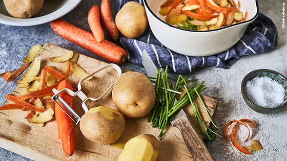 Arbeitsfläche mit Kartoffeln und Karotten, sowie deren Abfälle.