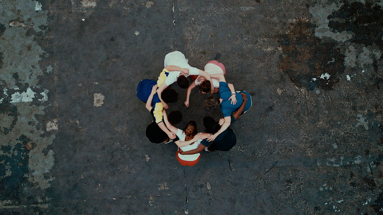 Eine Gruppe junger Erwachsener steht nach vorne gebeugt im Kreis.