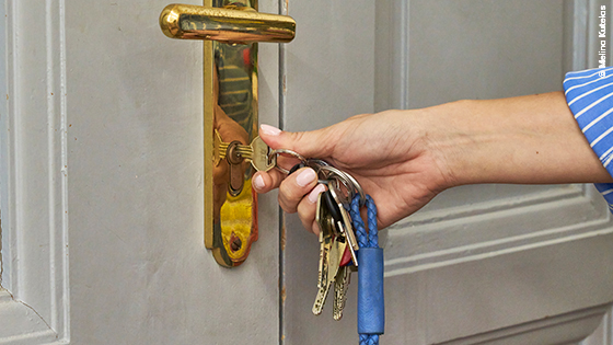 Frau sperrt Wohnungstür auf.