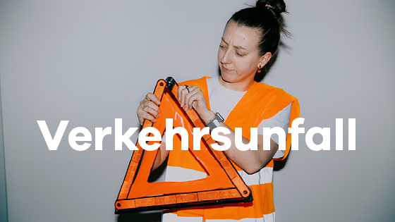 Junge Frau in Warnweste baut Warndreieck zusammen.