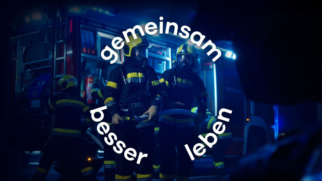 Zwei Feuerwehrleute der Freiwilligen Feuerwehr stehen in der vor dem Fahrzeug bei Nacht und halten den Wasserschlauch nach erfolgreichen Einsatz.