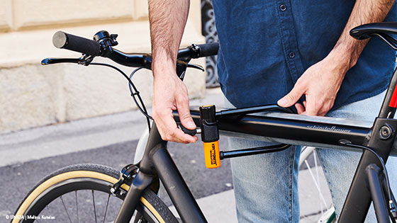 Mann steht an Fahrrad und versucht das Schloss zu öffnen