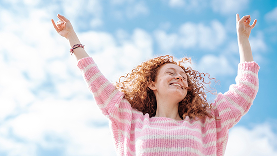 Frau streckt die Arme in die Luft und lächelt