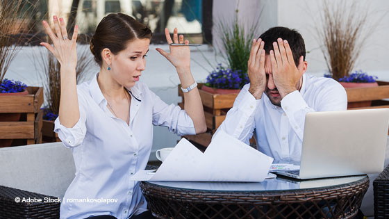 Frau und Mann sitzen an Tisch und verzweifeln aneinander