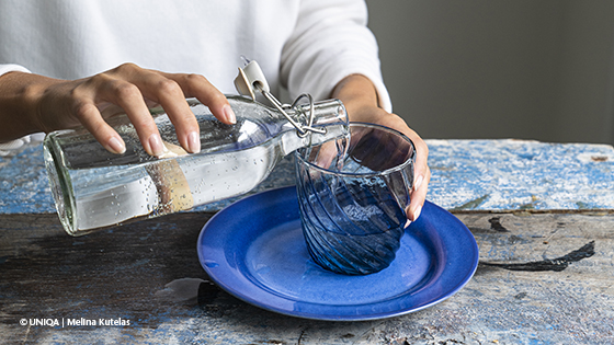 Frau leer Wasser aus einer Flasche in ein Glas