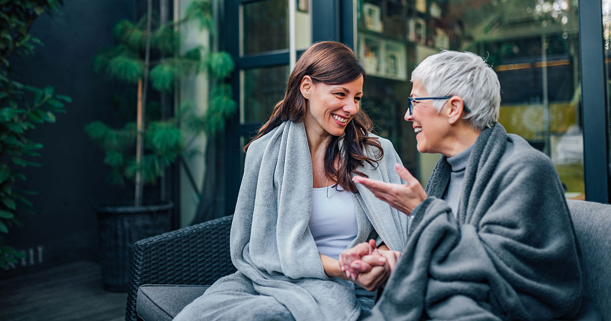 2 Frauen, im unterschiedlichen Alter, sitzen auf der Terrasse und unterhalten sich