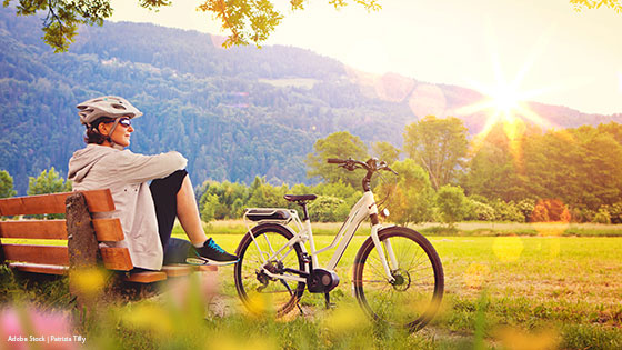 person entspannt auf wiese neben elektrofahrrad