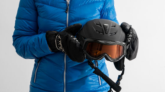 Person in blauer Jacke hält Skihelm