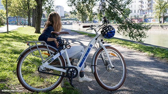 frau am donaukanal mit elektrofahrrad