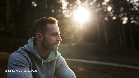 mann sitzt in wald am morgen