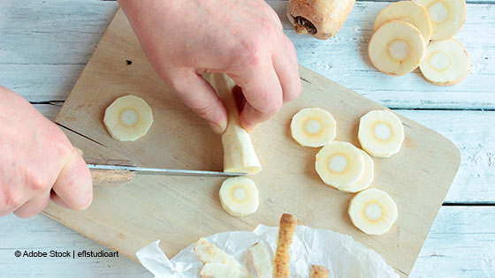 person schneidet pastinake