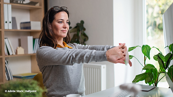 frau streckt arme aus an schreibtisch