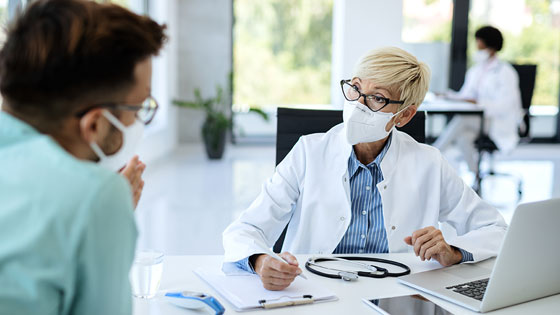 Ärztin mit FFP2-Maske im Gespräch mit Patienten