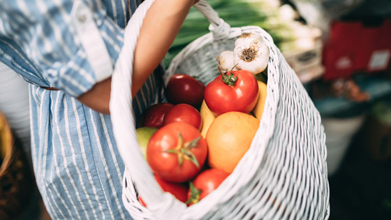 Frau mit Gemüsekorb am Arm