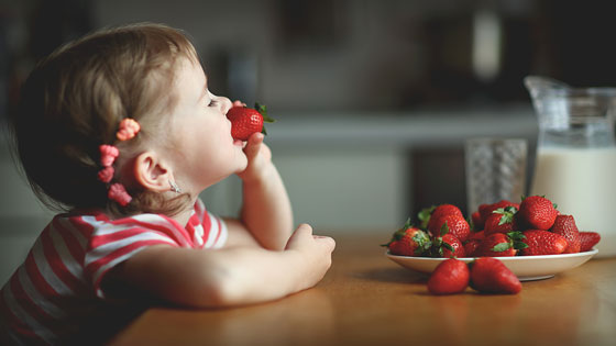 Mädchen isst eine Erdbeere.