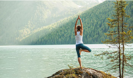 Frau macht Yoga am See.