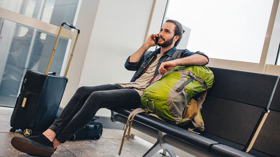 Mann sitzt am Flughafen, wartet und telefoniert