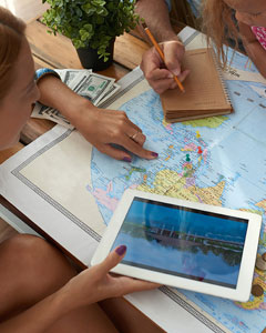 Familie sitzt vor Landkarte und sucht Reiseziel