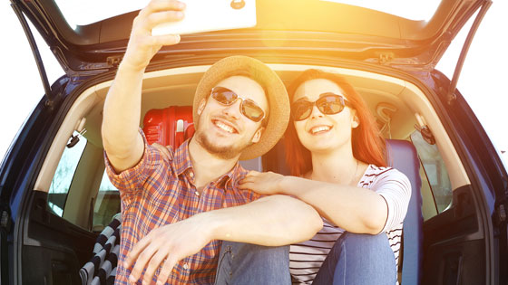 Mann und Frau machen ein Selfie im Kofferraum.