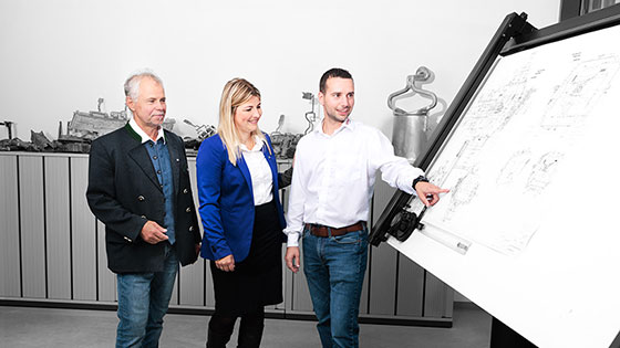 Drei Personen vor Planzeichnung