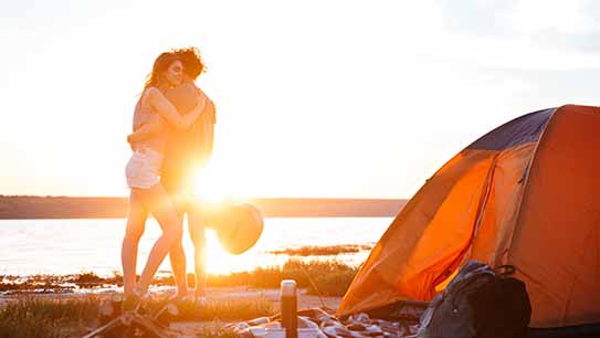Paar umarmt sich am Strand neben einem Zelt